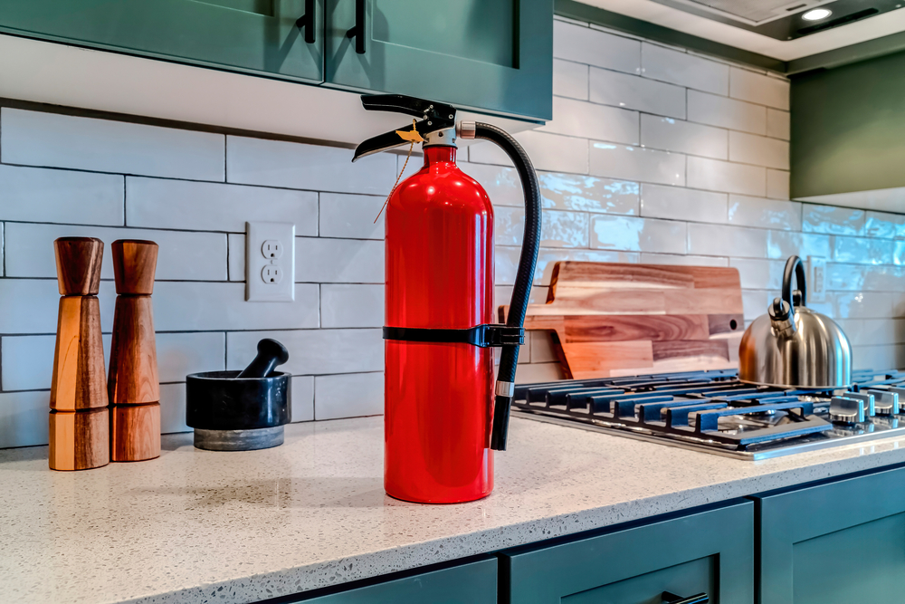 A close up of a red fire extinguisher on a kitchen counter.