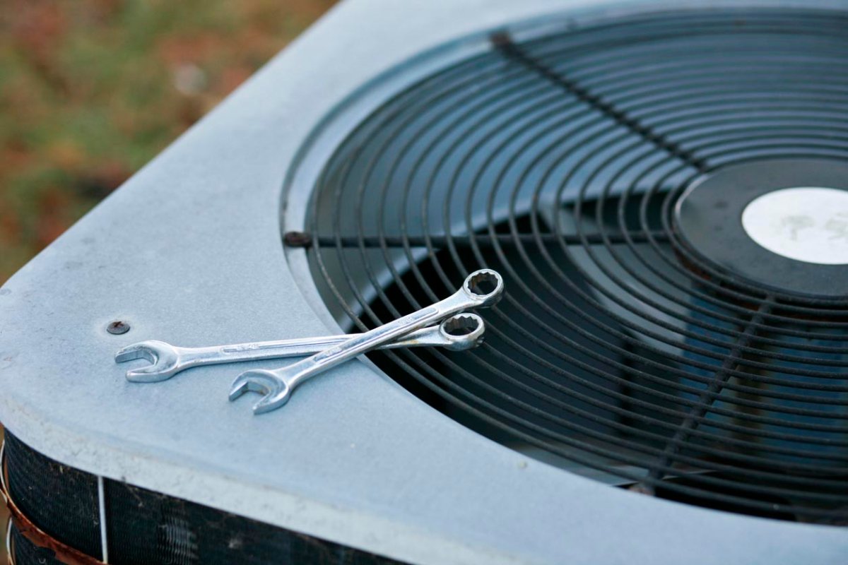 A close up of wrenches on an AC unit.