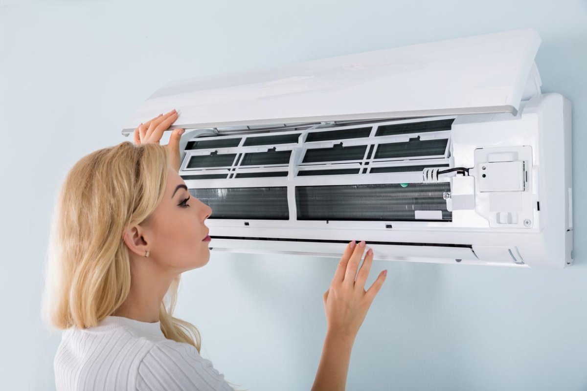 A woman peers inside an AC unit.