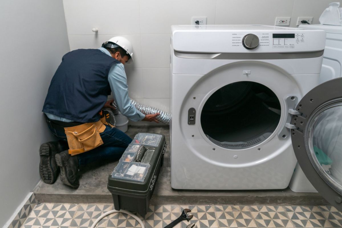 A technician fixes a washing machine. 
