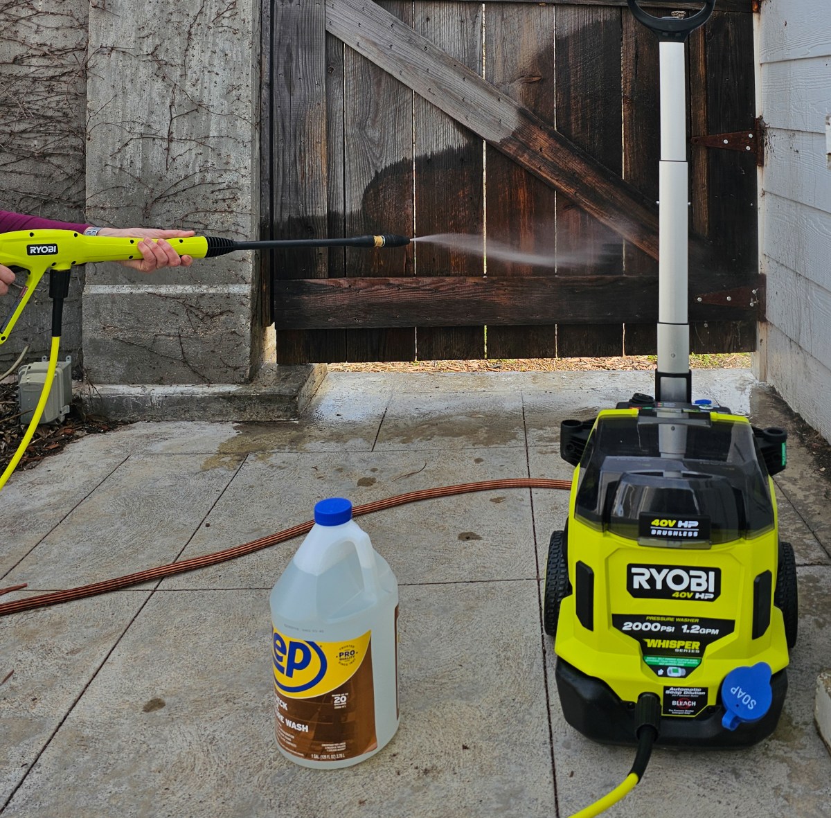Someone using the Ryobi 2,000 PSI 1.2 GPM Electric Pressure Washer to clean a fence during testing.