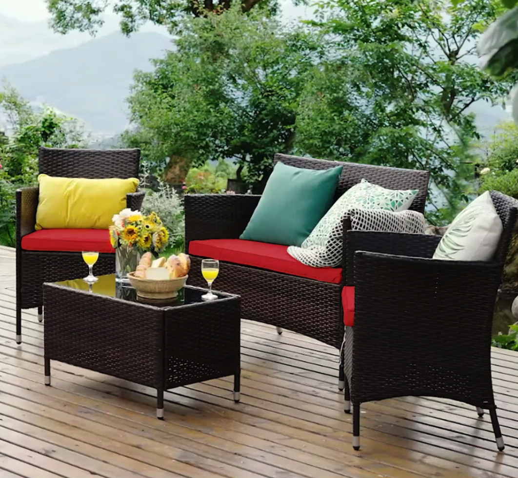 Costway 4-Piece Rattan Patio Furniture Set set up on a deck with decorative pillows