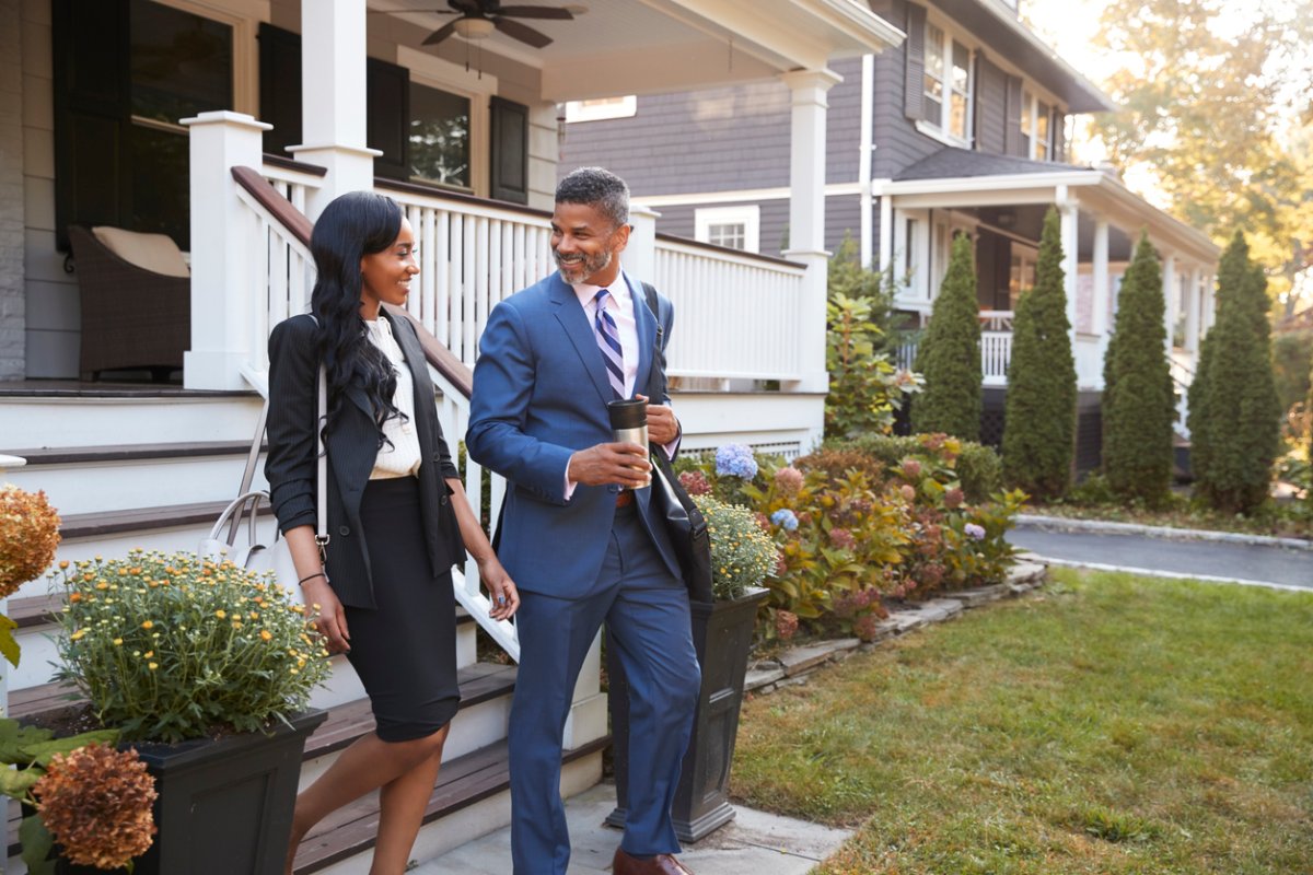 Two people in office attire leave a grey home.  