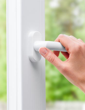 A close up of a hand on a white door handle. 