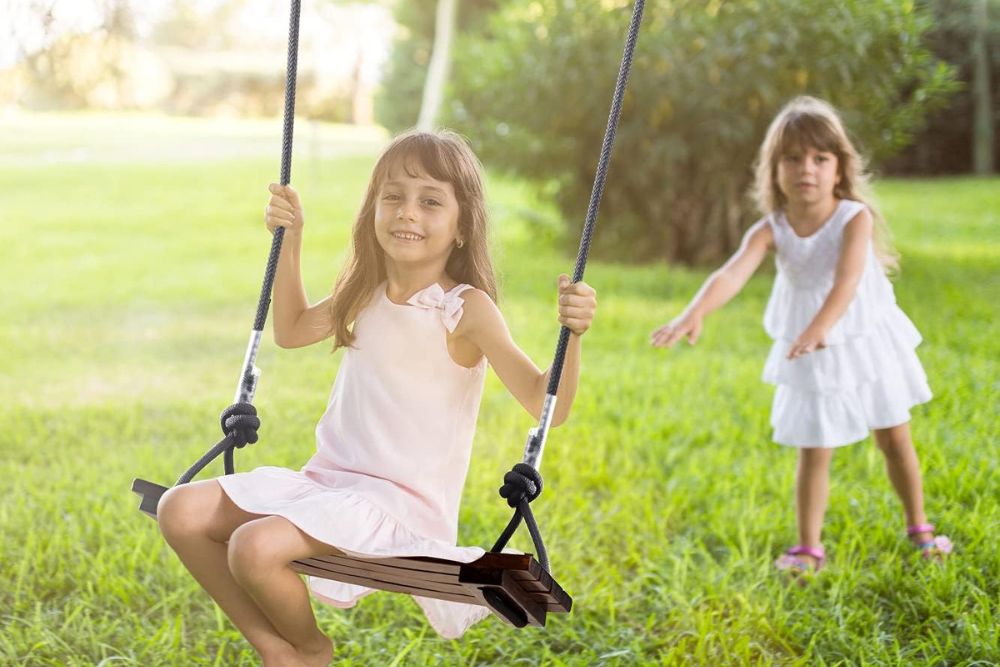 Two young girls playing on a swing in the garden