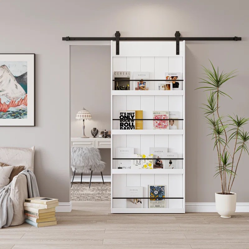White barn door hanging on an upper rail doubles as a bookcase.