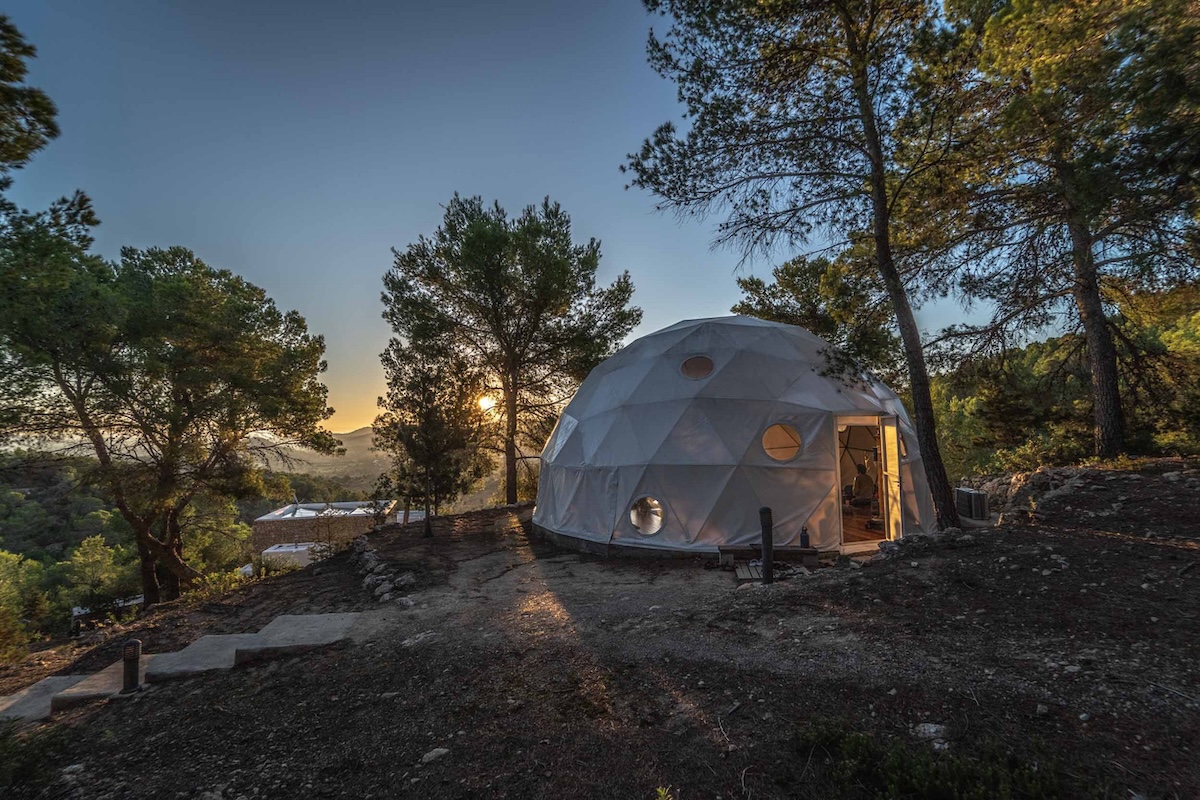 A dome home with circular windows in front of a sunset.