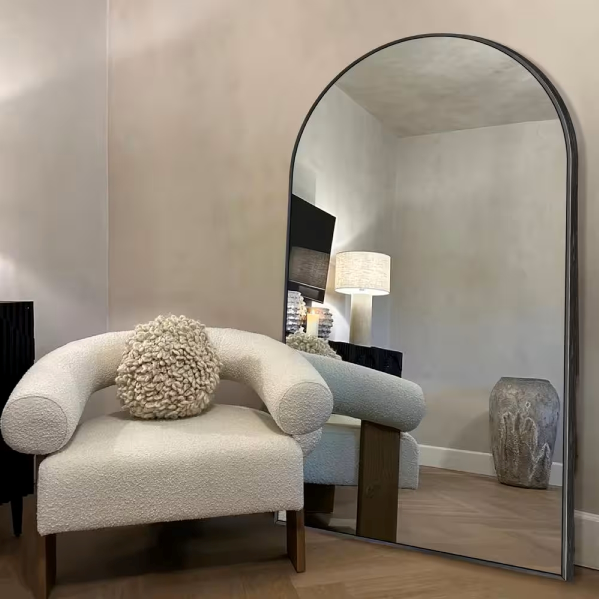 A large mirror behind a white modern chair.