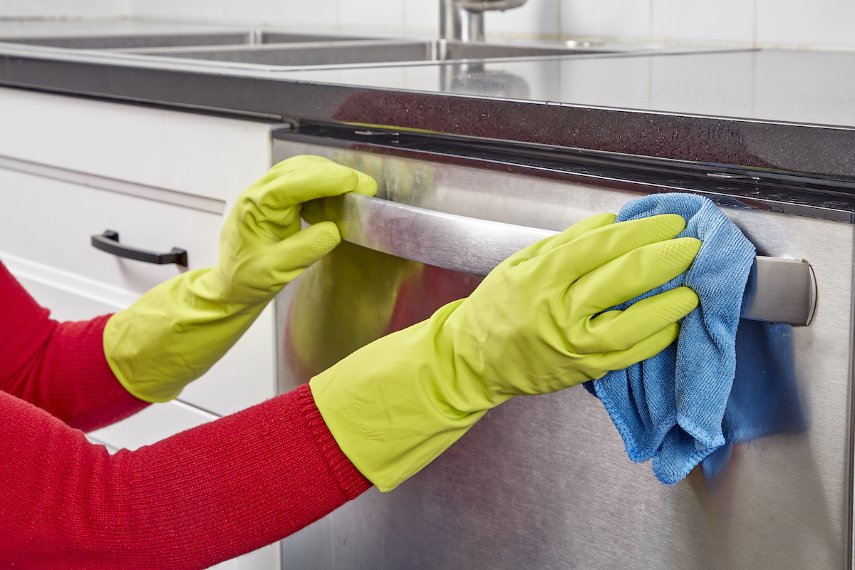 Woman wipes the handle of her dishwasher.