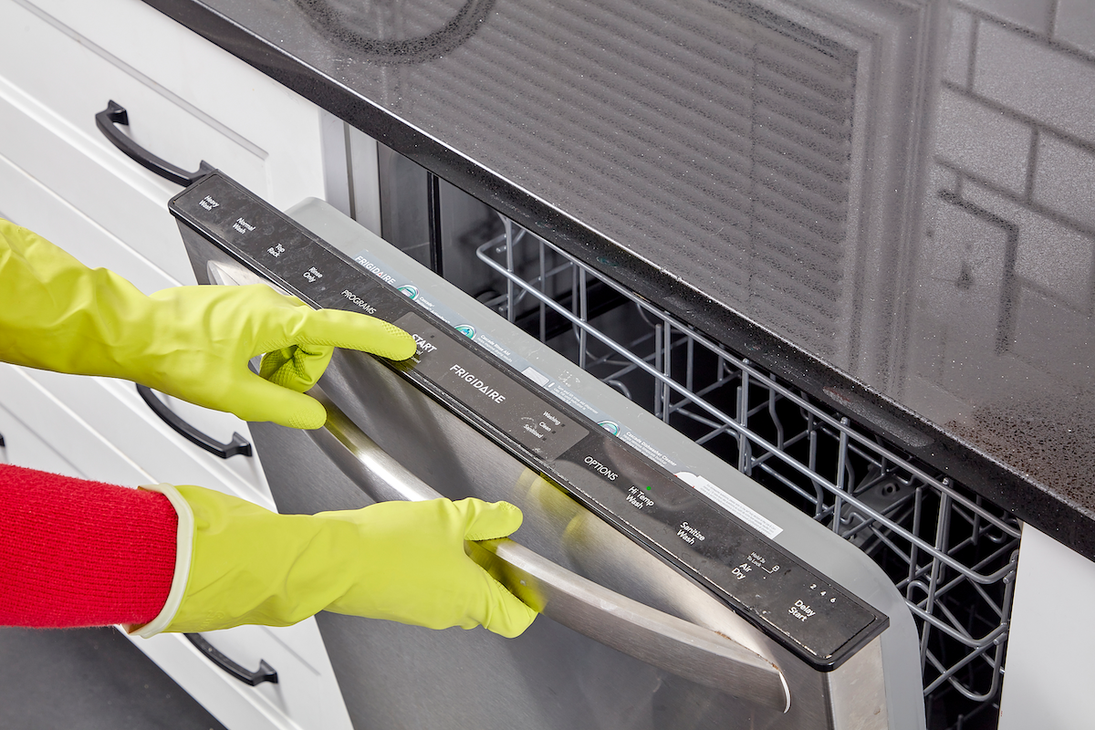 Woman pushes the "start' button on her dishwasher.