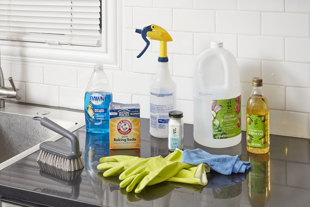 Materials needed to clean a stainless steel sink, including spray bottle, dish soap, olive oil, and more.