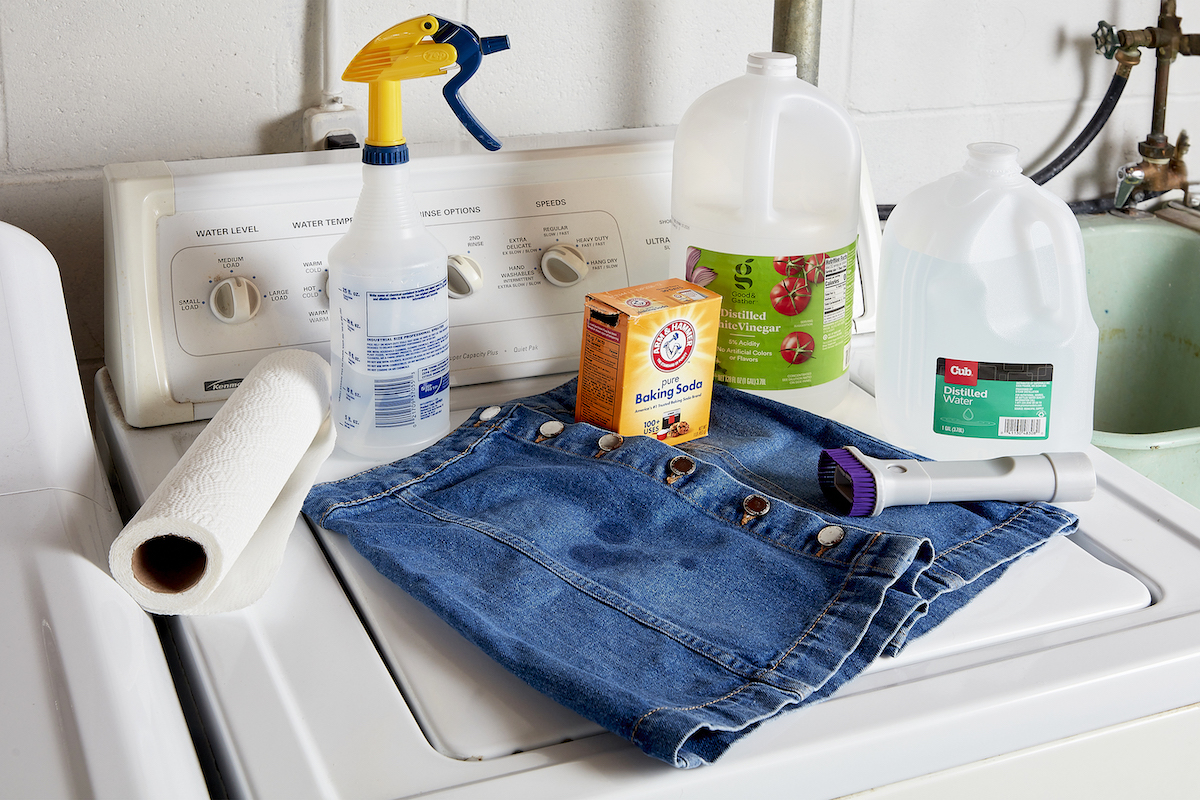 Denim skirt and the materials needed to remove stains from it, including baking soda, vinegar, and paper towels.