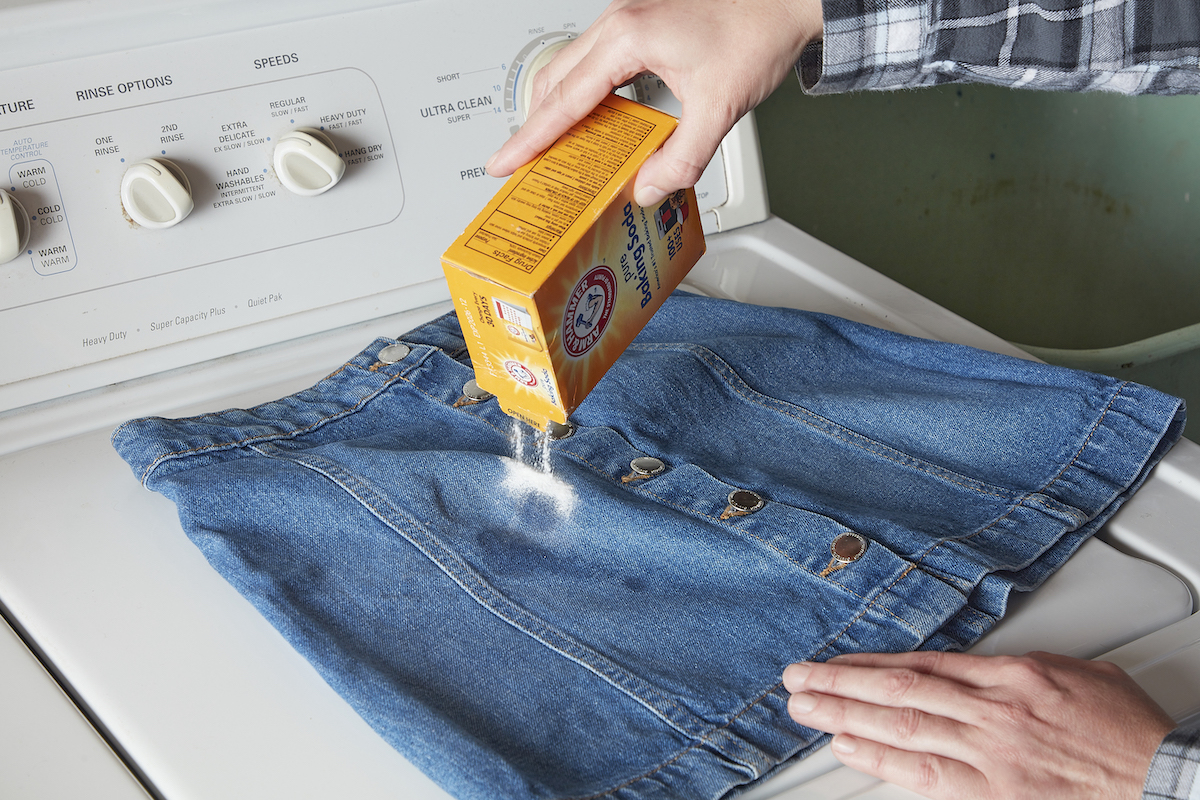 Woman sprinkles baking soda on a stained denim skirt.