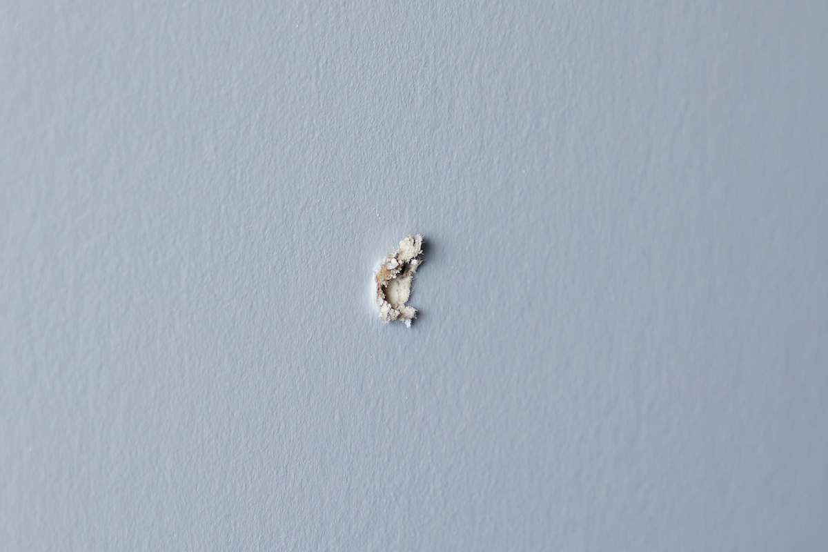 A small hole in drywall that's painted light blue.
