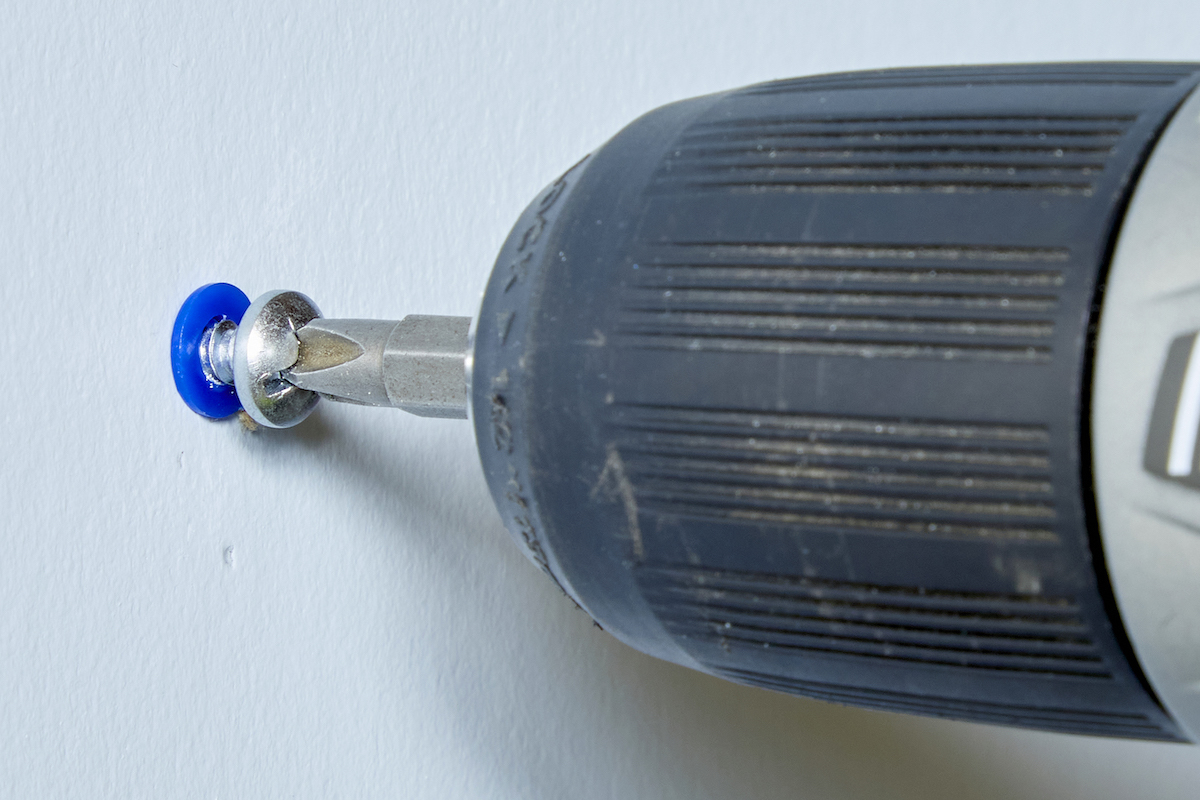 Using a drill to pull a screw a little bit out of a drywall anchor.