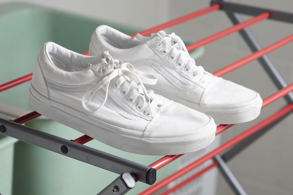 Clean white sneakers are drying on a drying rack.