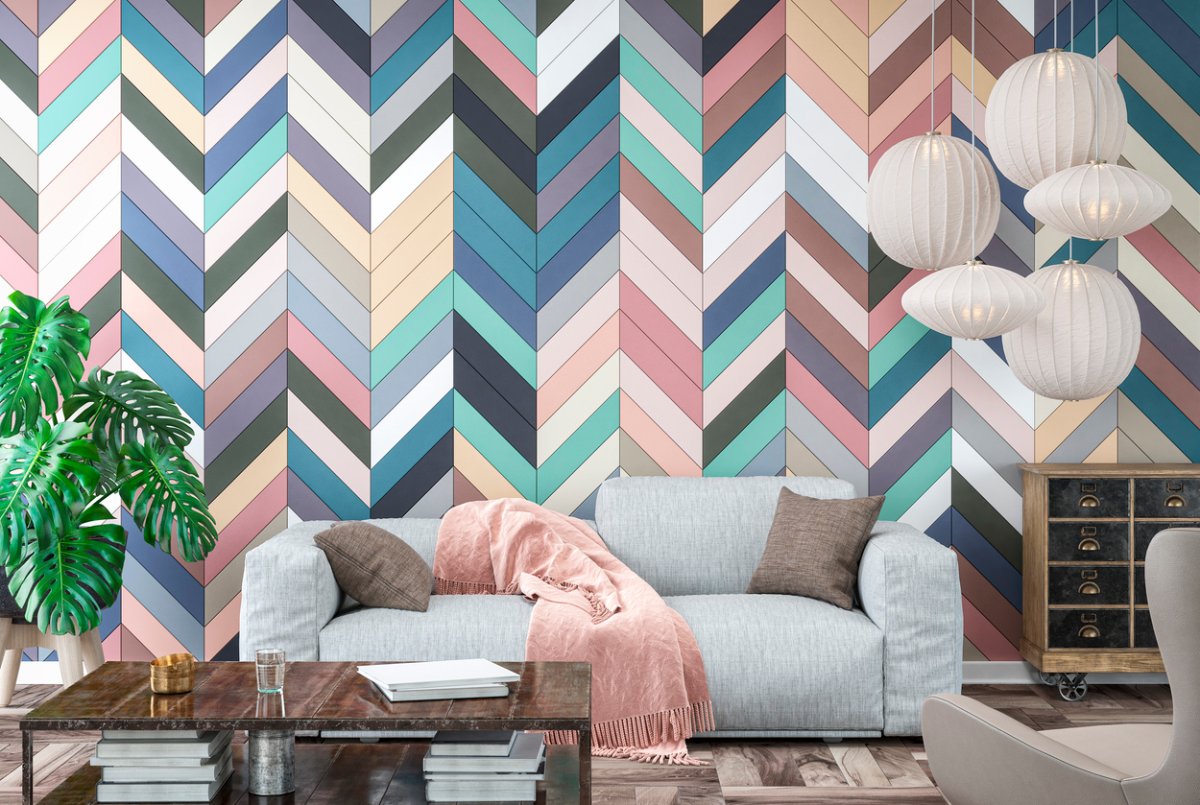 Modern living room with gray sofa, chair, table and decoration on hardwood floor in front of multicolored herringbone pattern tiled wall.