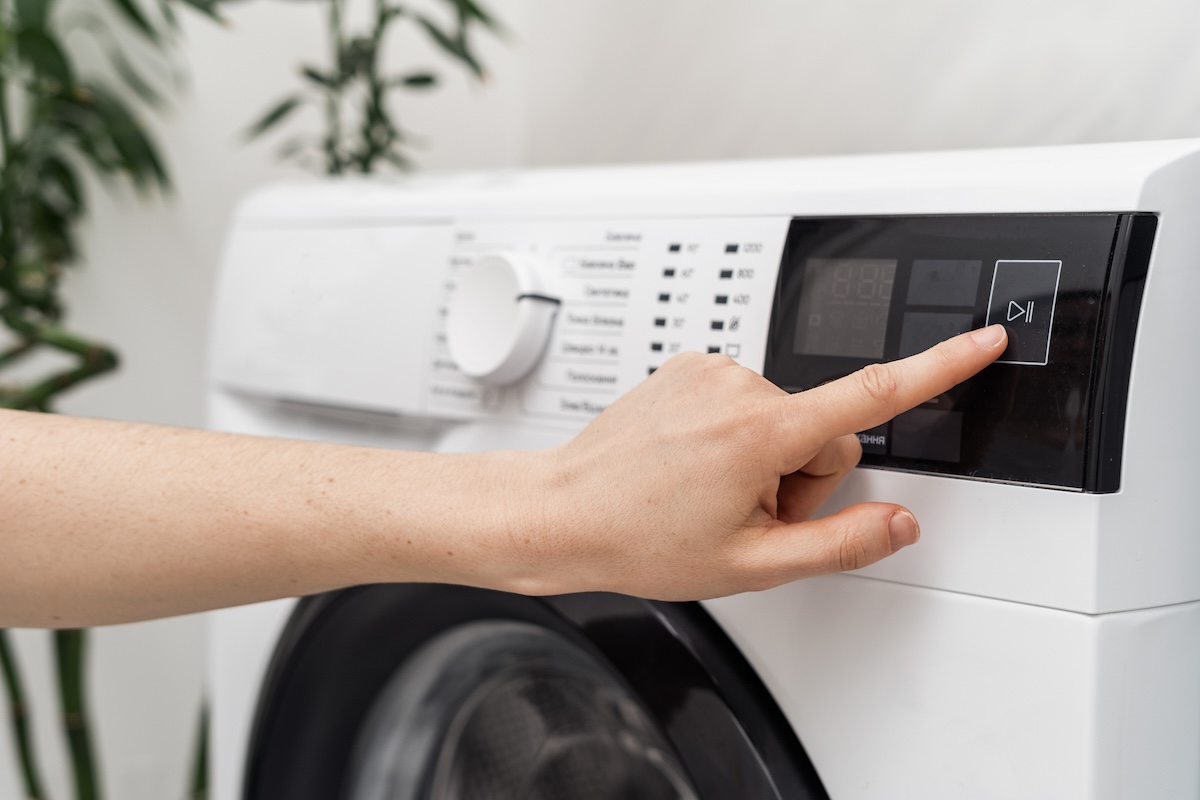 A person starting an efficient washing machine.