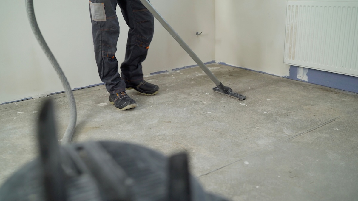 A person vacuuming a garage floor with a wet/dry vacuum.