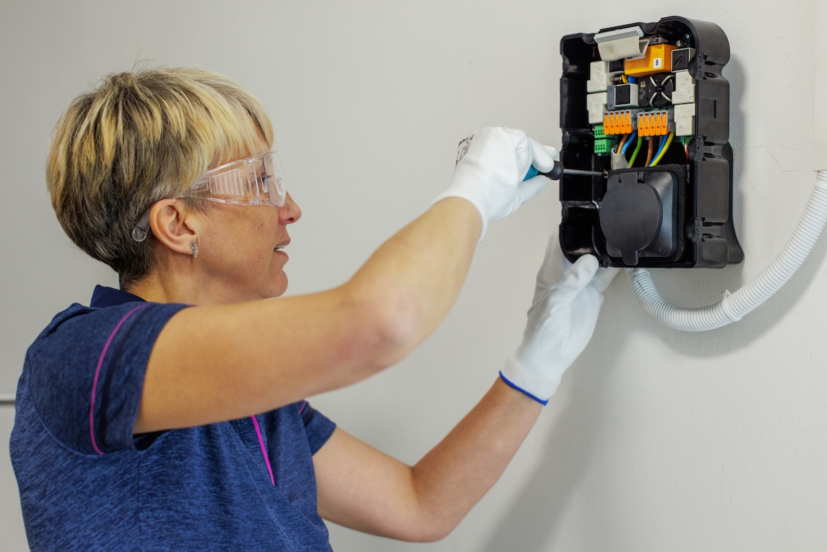 A person installing an electric vehicle charger in a home garage.