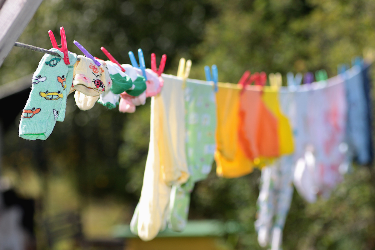 Colorful clothes are pinned to a clothesline with colorful plastic clothespins.