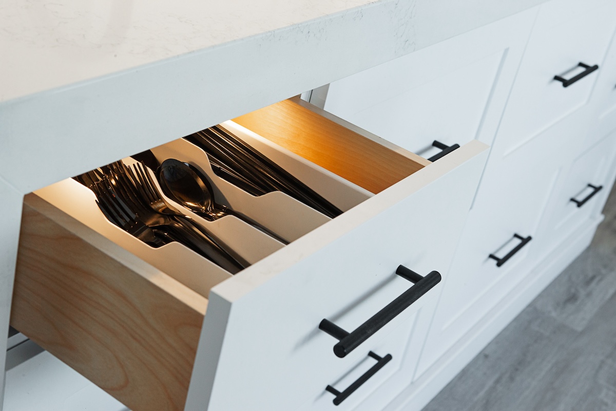Open silverware drawer with lights and black silverware. The back of drawers are ideal for hiding cash in.