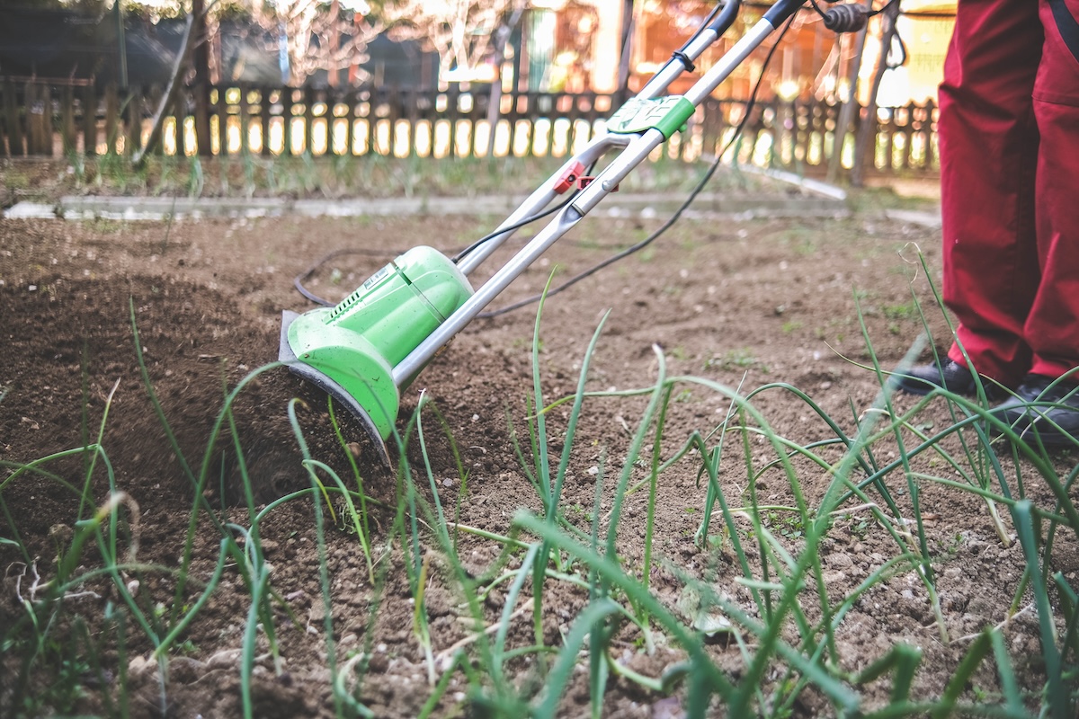 Person using an electric garden tiller.