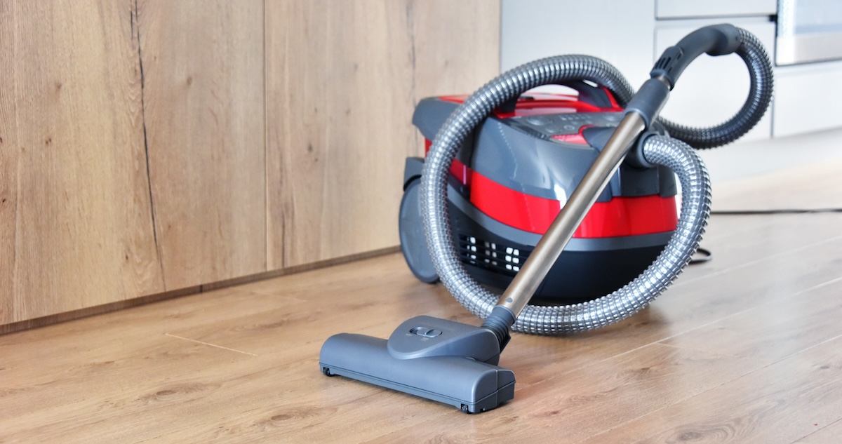 Red and great canister vacuum on hardwood floor.