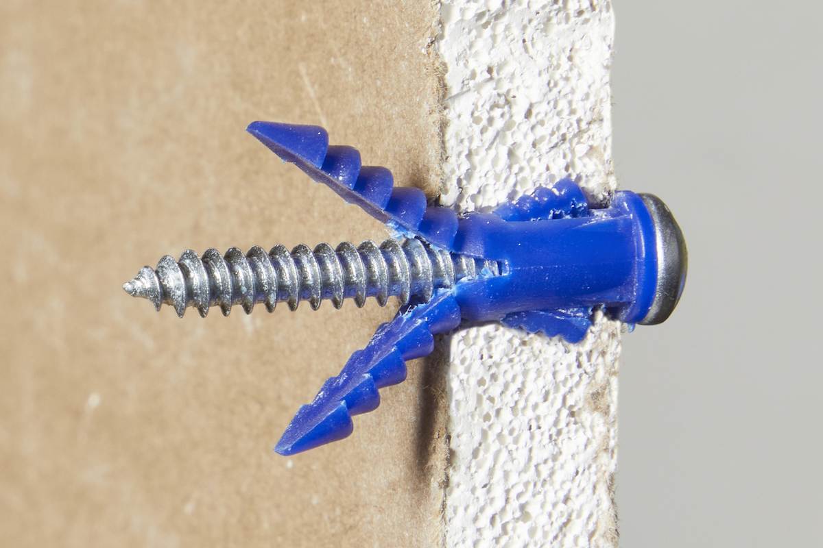 Side view of an expansion drywall anchor through a piece of drywall.