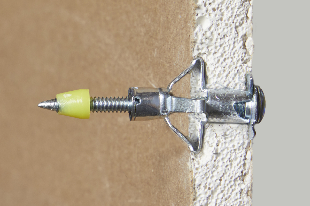 Side view of a molly bolt anchor through a piece of drywall.