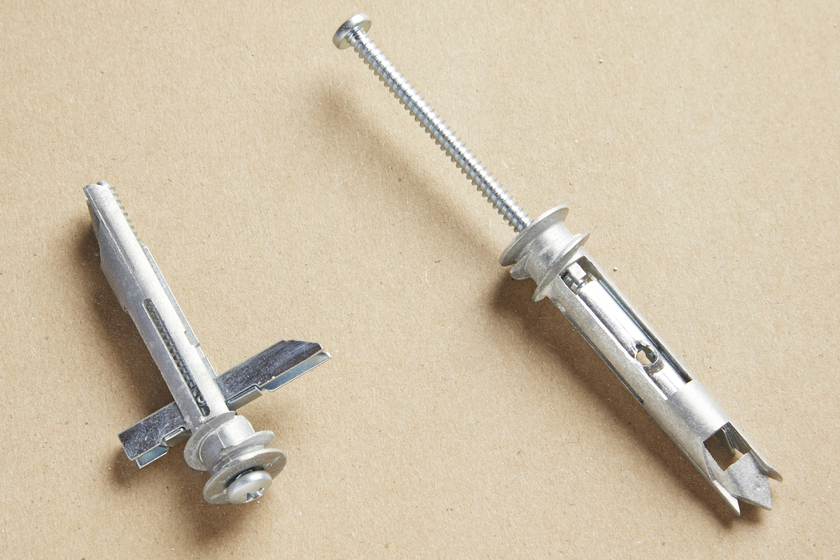 Two self drilling toggle anchors on a brown background.