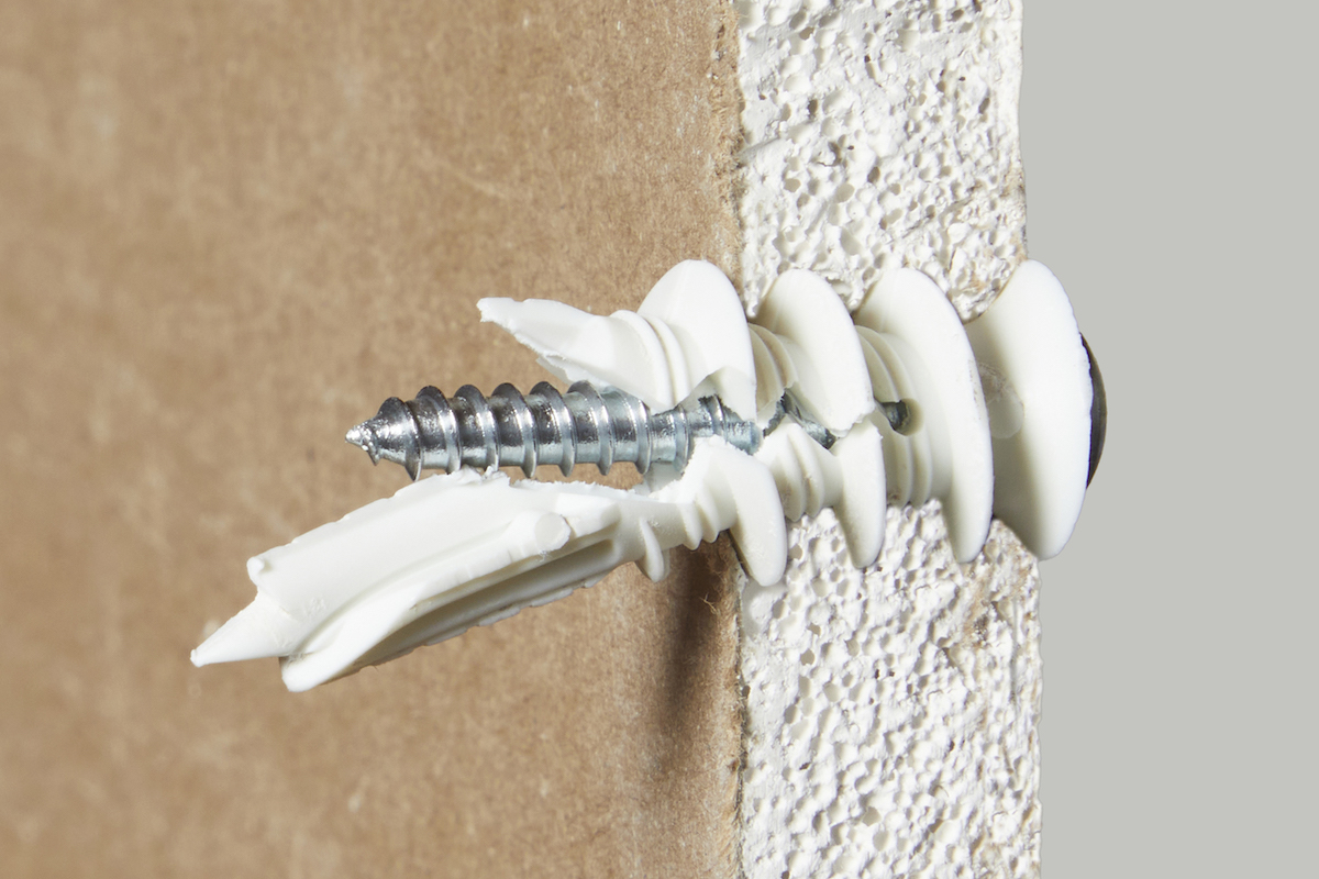 A side view of a threaded drywall anchor inserted into drywall.