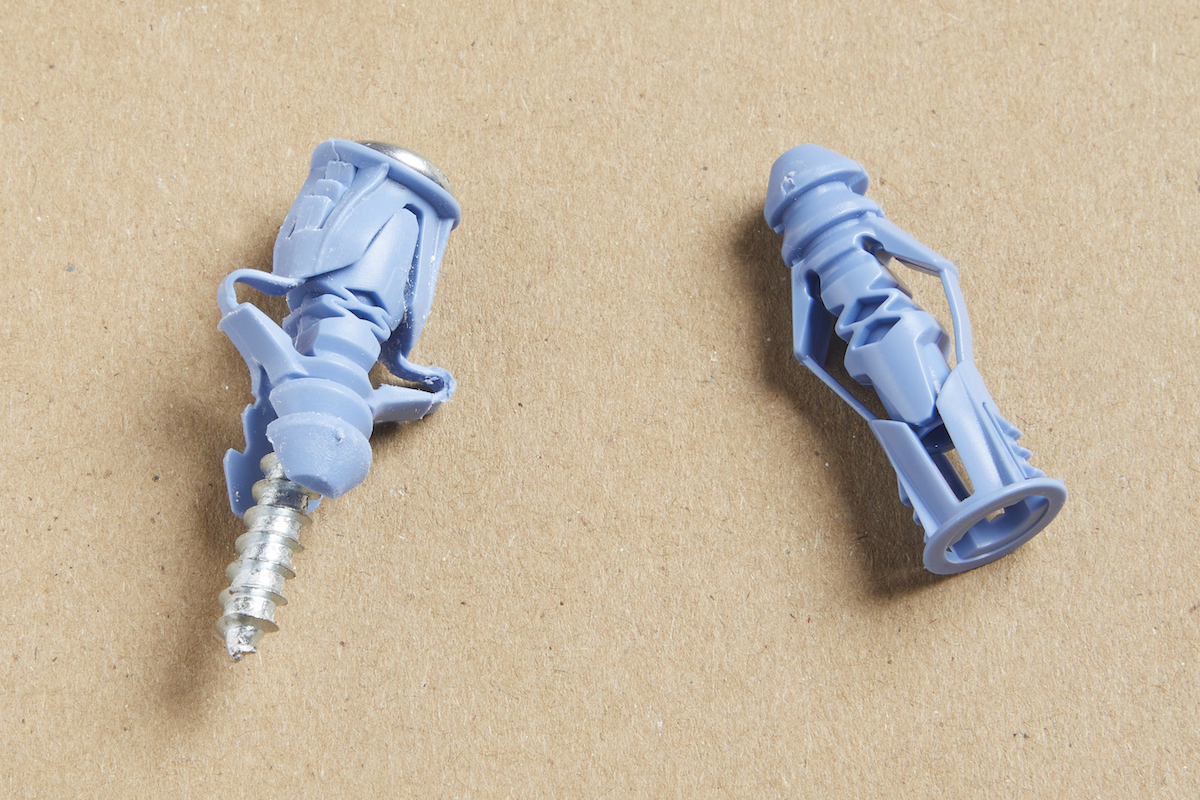 Two light blue winged plastic drywall anchors against a brown background.