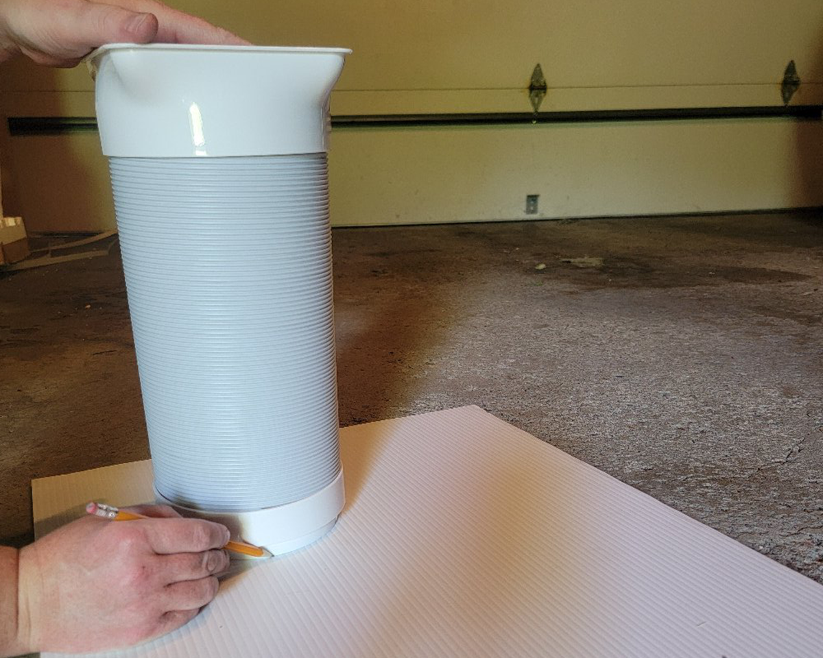 A person tracing the hole to be cut out to vent a portable ac unit out a crank window.