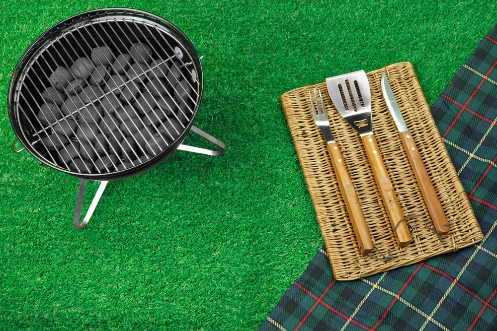 Summer Picnic Scene On The Lawn. Portable Barbecue Grill, Tools And Blanket. Top View
