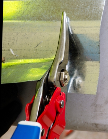 Person cutting through sheet metal with red Lenox aviation tin snips