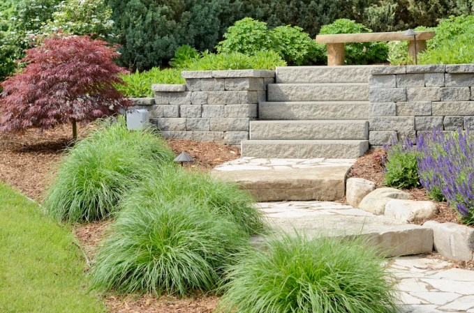 Sustainable hardscaping in a residential outdoor space with a retaining wall, stairs, and a permeable stone pathway.