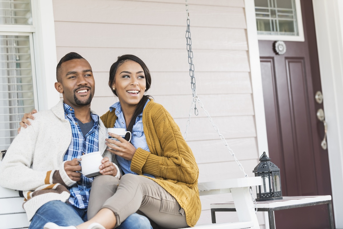 A young couple chatting with neighbors on the front porch.