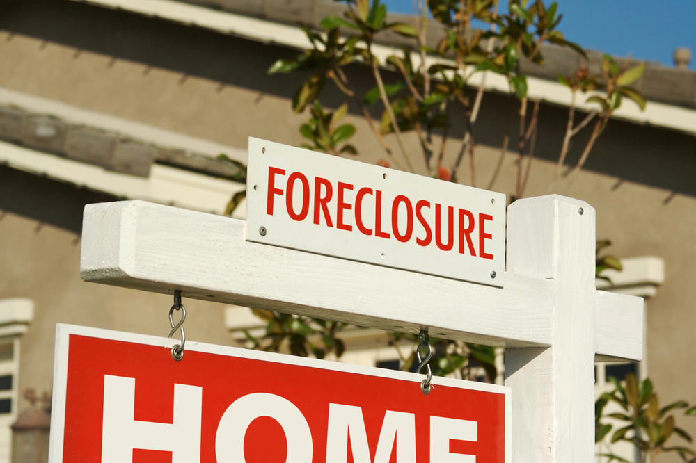 A red 'Foreclosure' sign is seen in front of a house. 