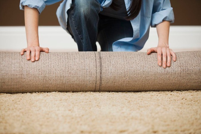 A close up of a person rolling out a carpet.