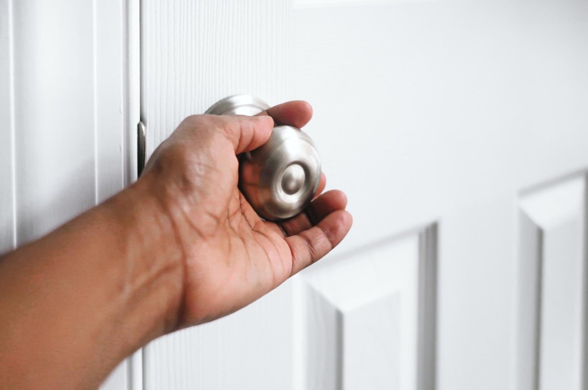 A close up of a person holding a silver doorknob. 