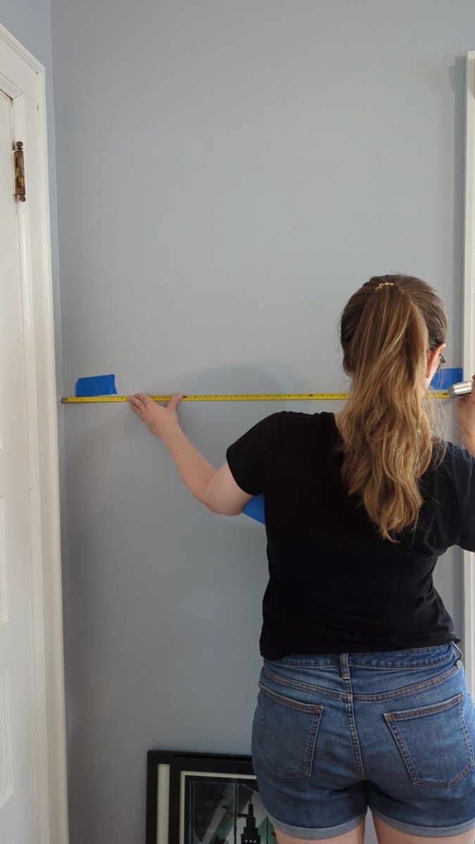 Measuring and marking exactly eye level with painter's tape for picture-hanging