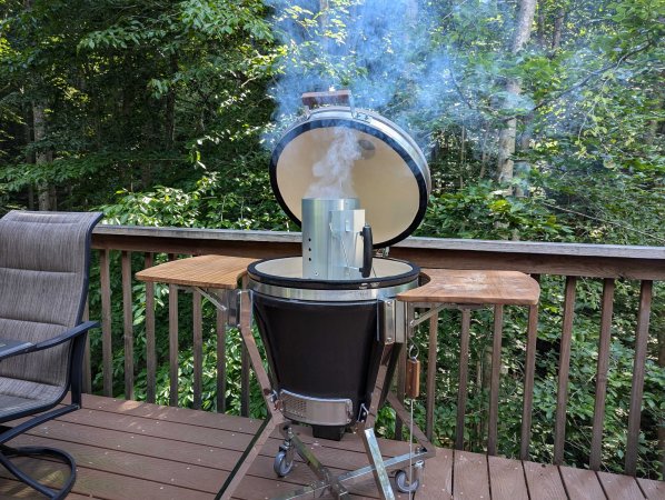 Stainless steel charcoal chimney in a NewAge Kamado Smoker on a deck