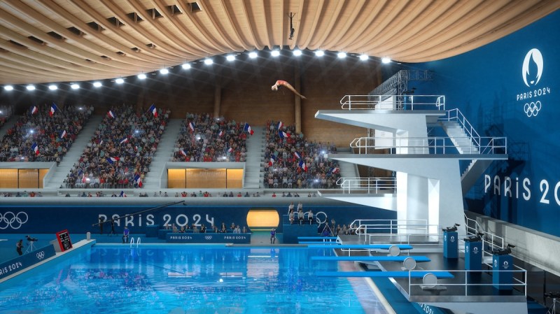 An olympic diver leaping off a diving board in the Paris Olympics aquatic center.