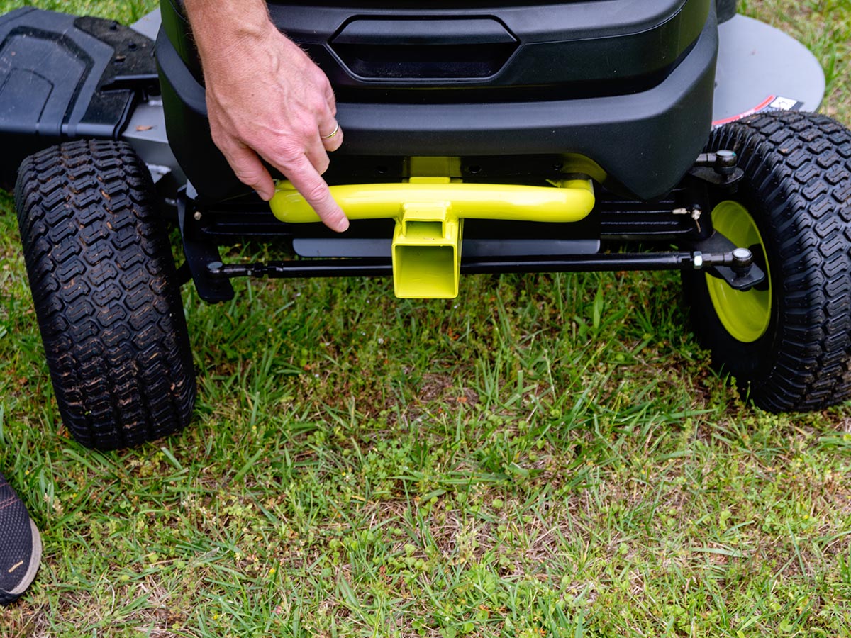 Person's hand on yellow Ryobi Lawn Tractor hitch