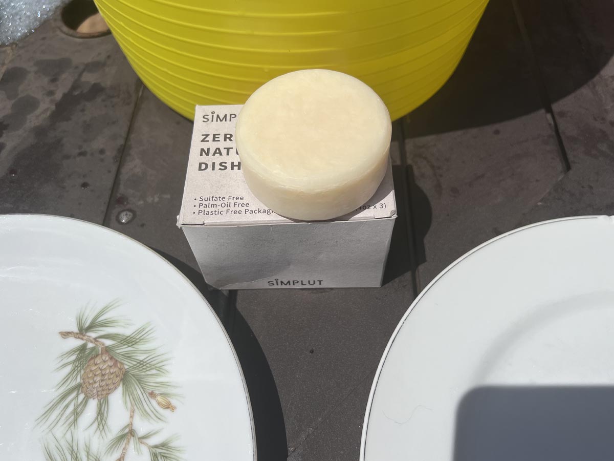 Bar of Simplut dish soap next to two white plates with pine cones on them.