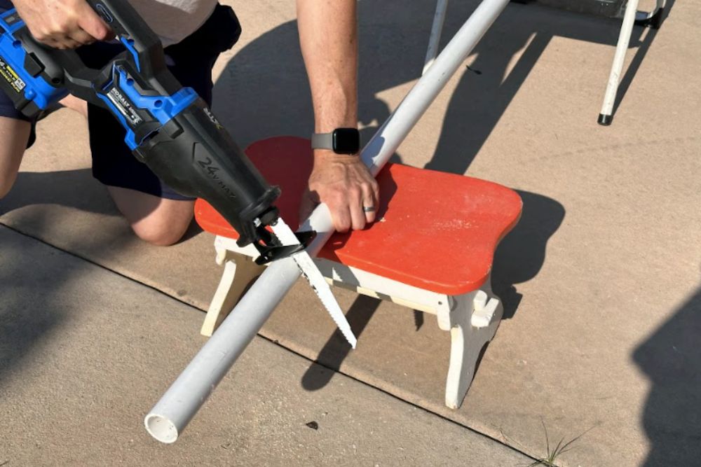 Person using Kobalt reciprocating saw to cut PVC pipe