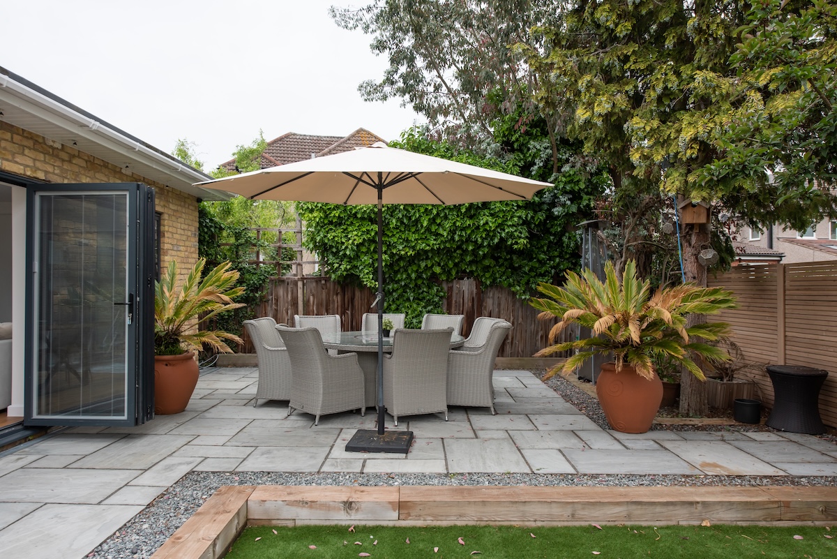 Cement patio in the backyard with a table and umbrella. 