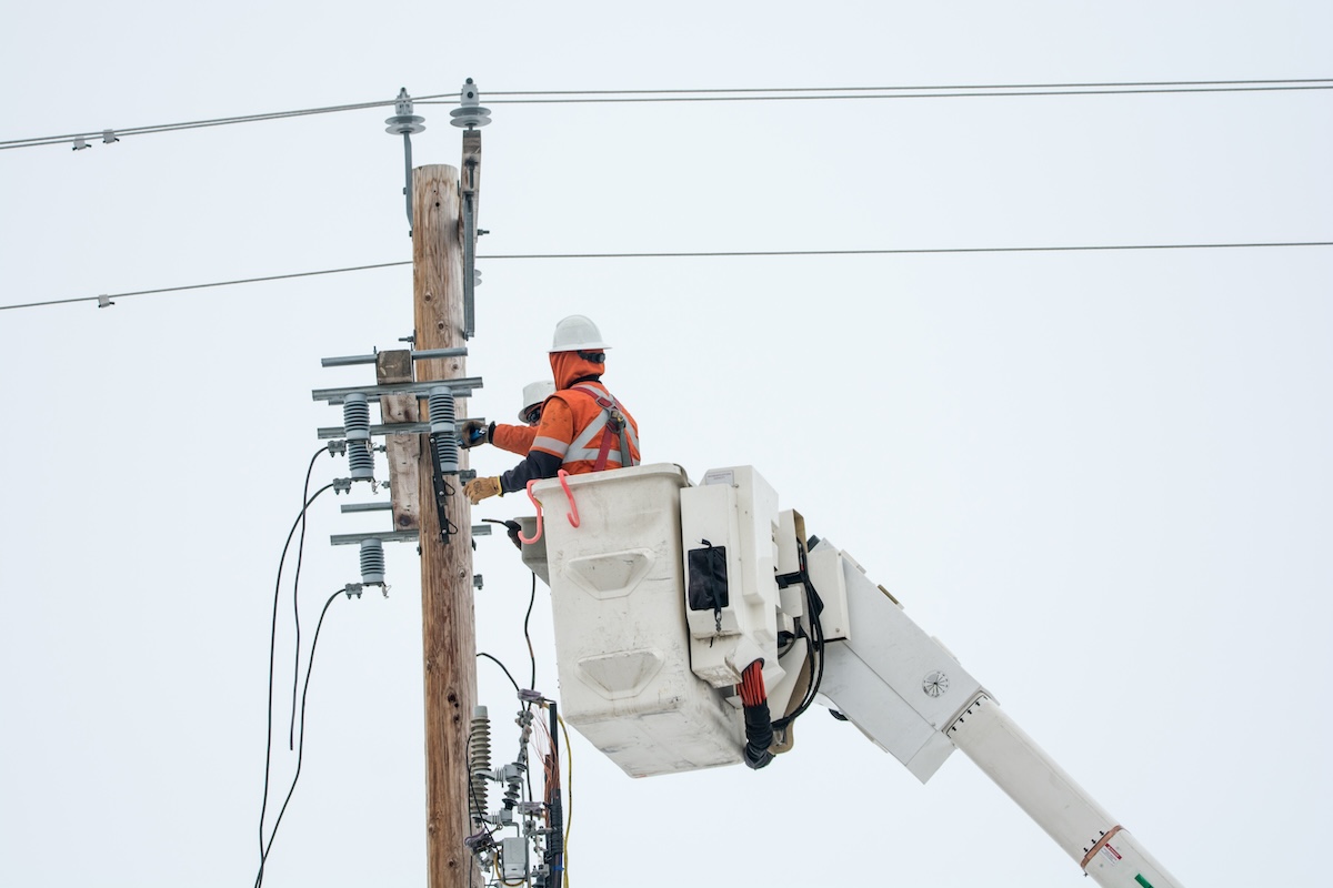 Two line workers repairing electric lines. 