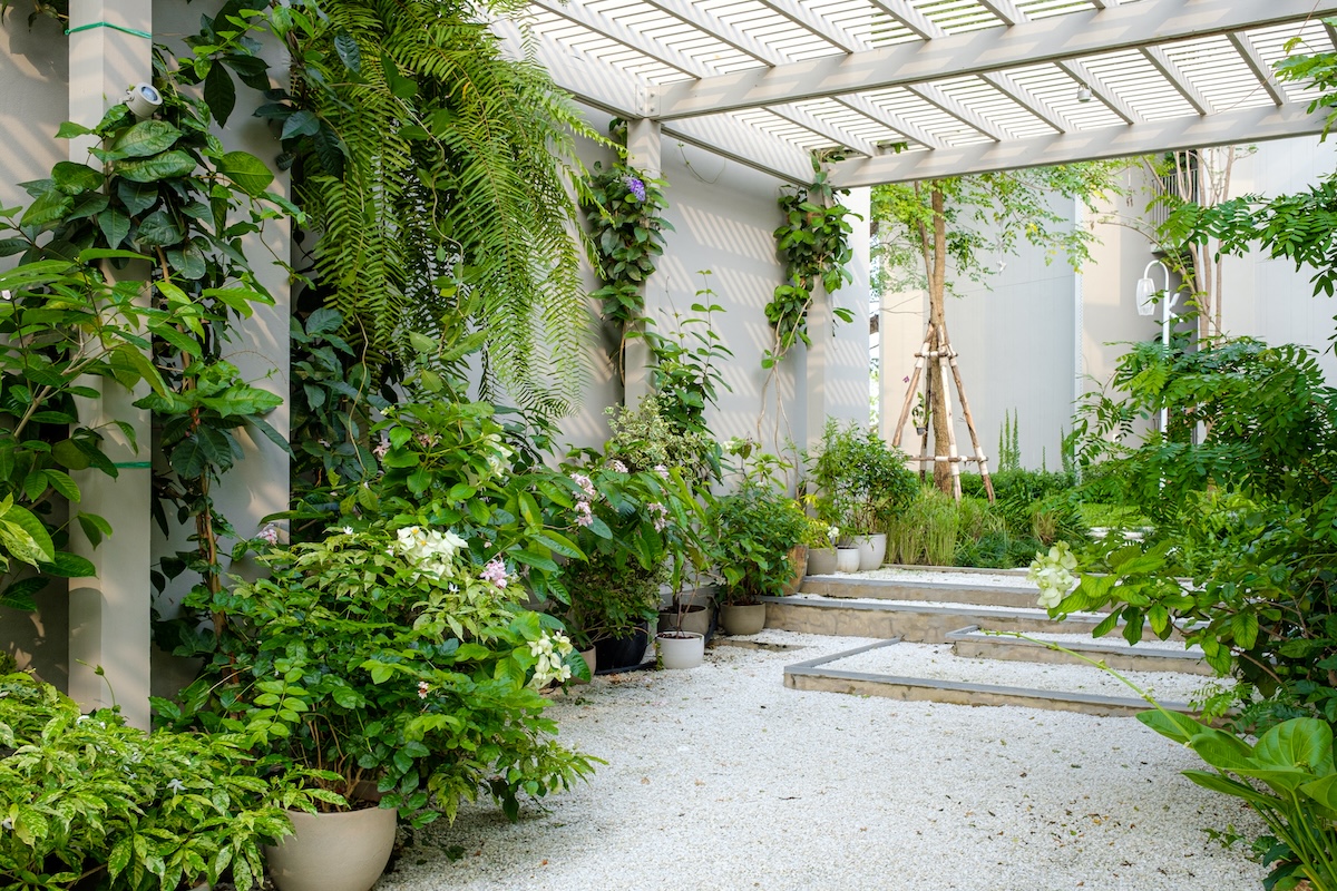 Gravel patio with parabola and green planters.